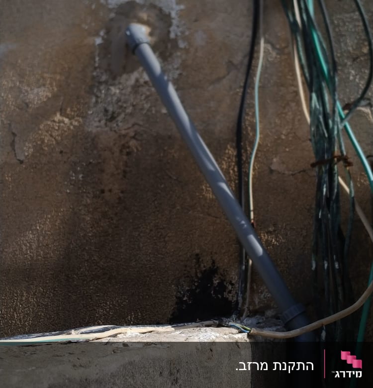 צינור פלסטיק אפור מחובר לקיר עם חוטים